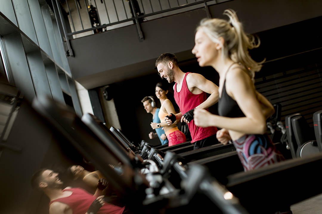 young people running on treadmills in modern gym